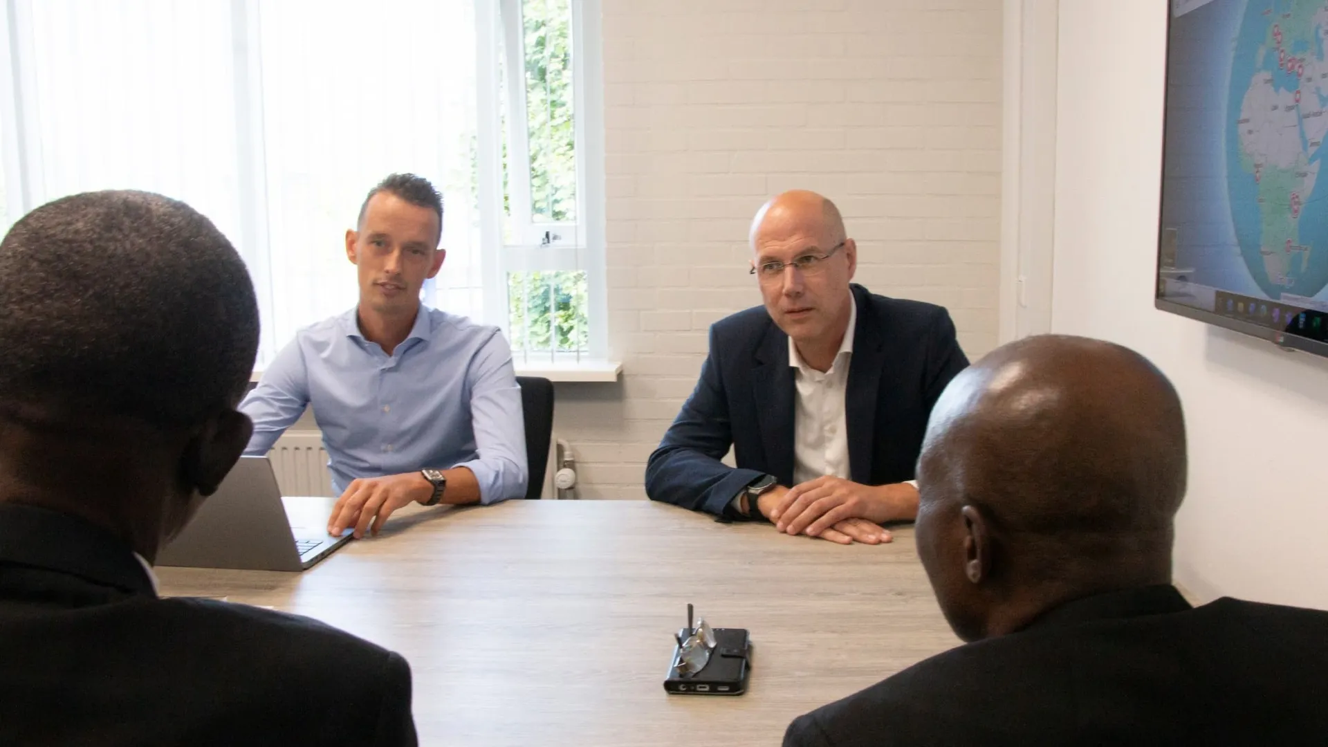 Twee bureaumedewerkers in gesprek met twee partners uit Nigeria