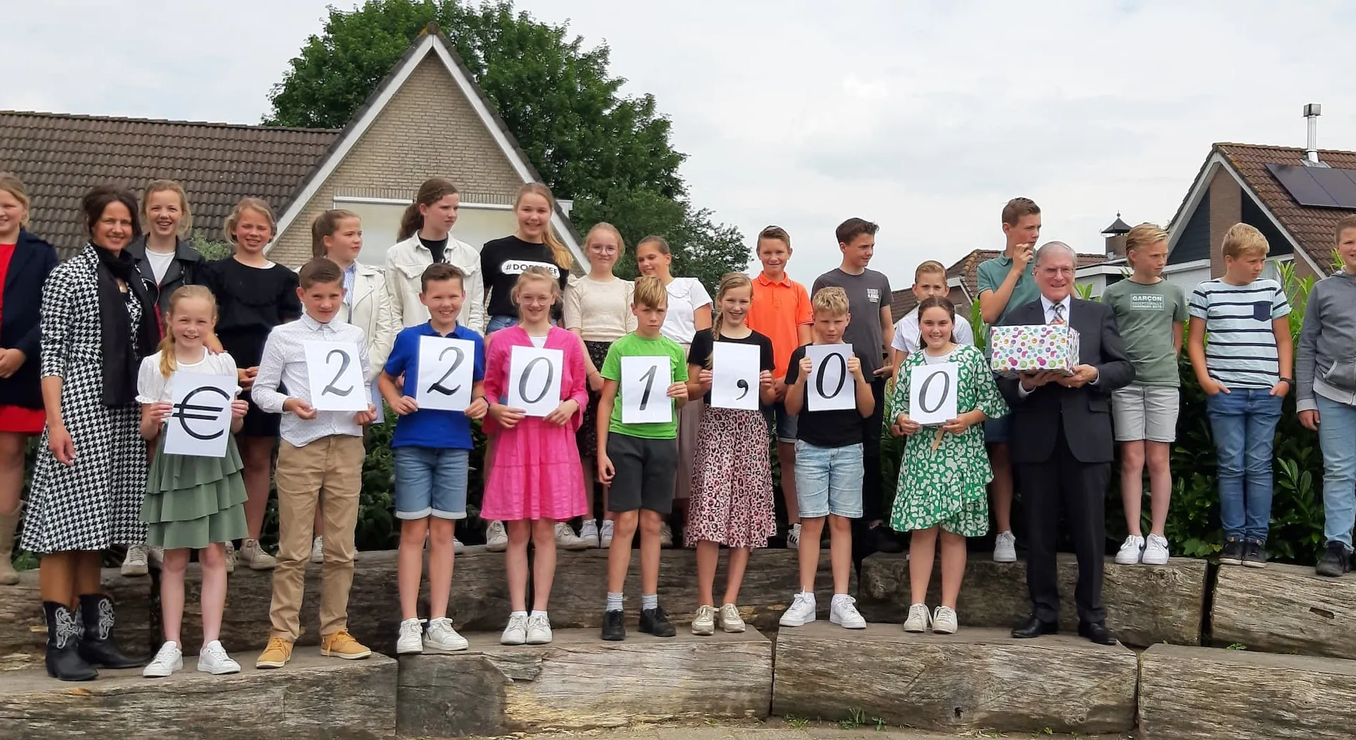 Klassenfoto die A4'tjes met een eindbedrag toont.