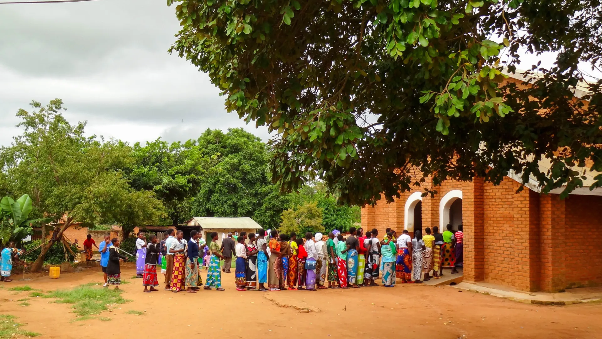 Een rij mensen staan voor een Afrikaanse kerk.
